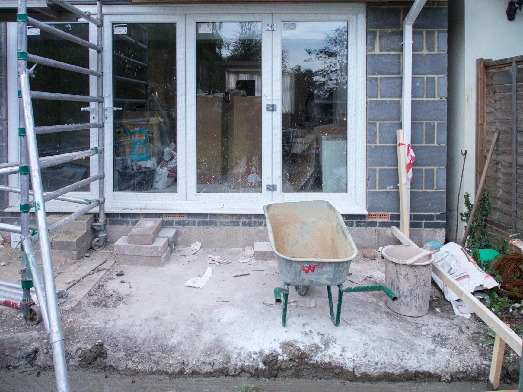 外壁塗装の工期中に足場とシートで覆われた晴天の戸建て住宅
